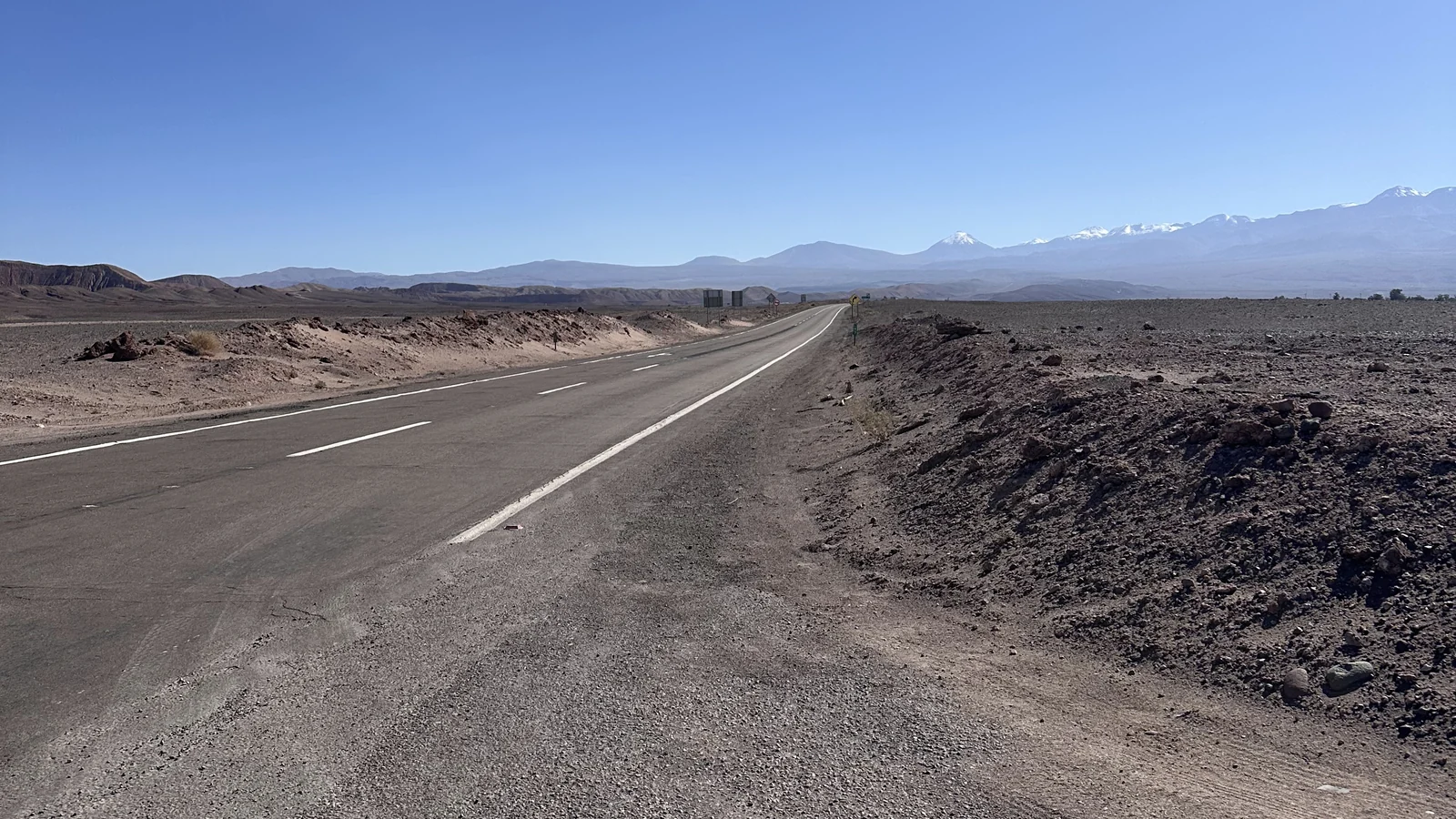 La strada asfaltata che esce da San Pedro de Atacama verso la Valle de la Luna, con i vulcani all'orizzonte