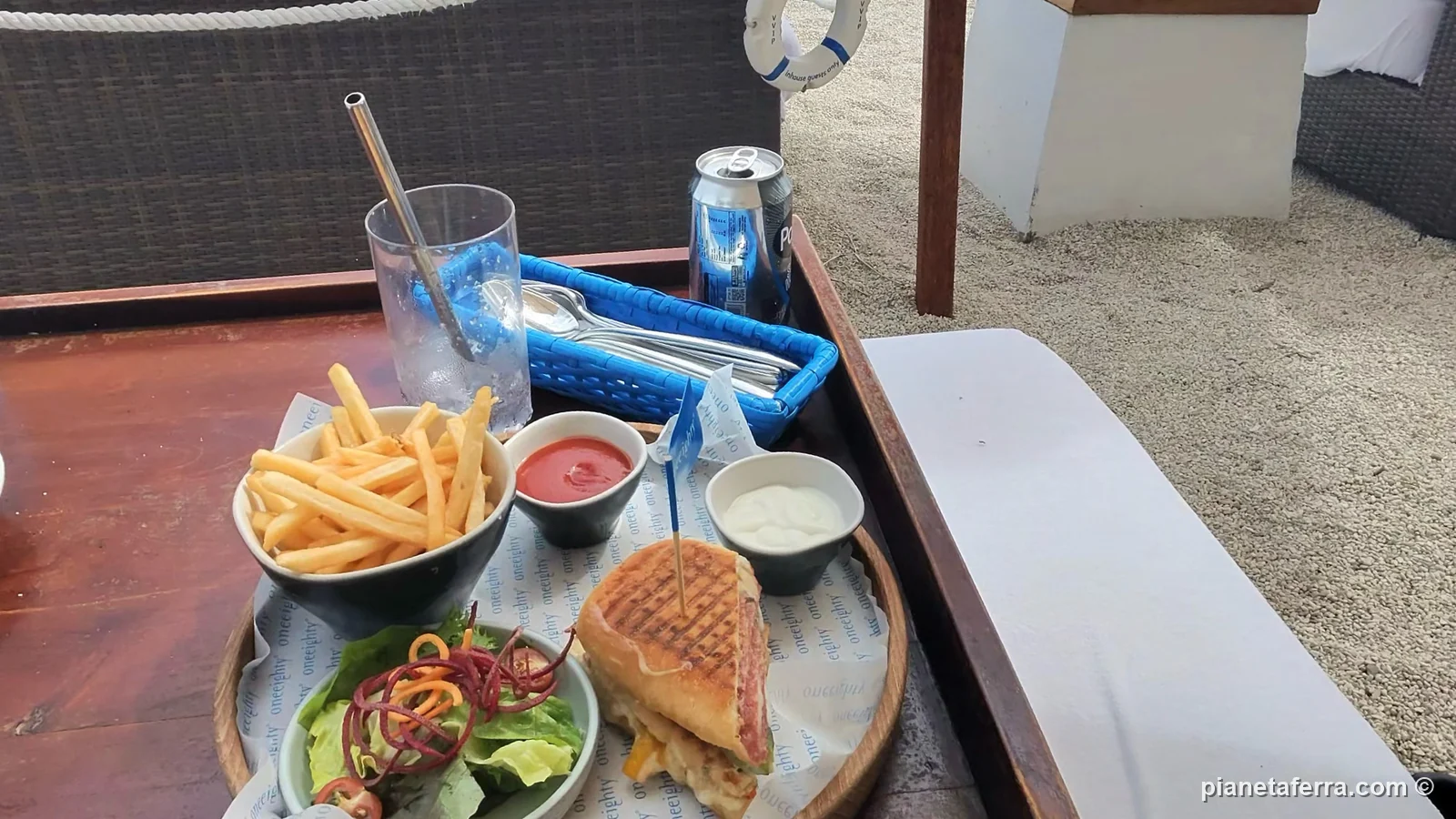 Lettino in un beach club di Bali con patatine e panino sul tavolino