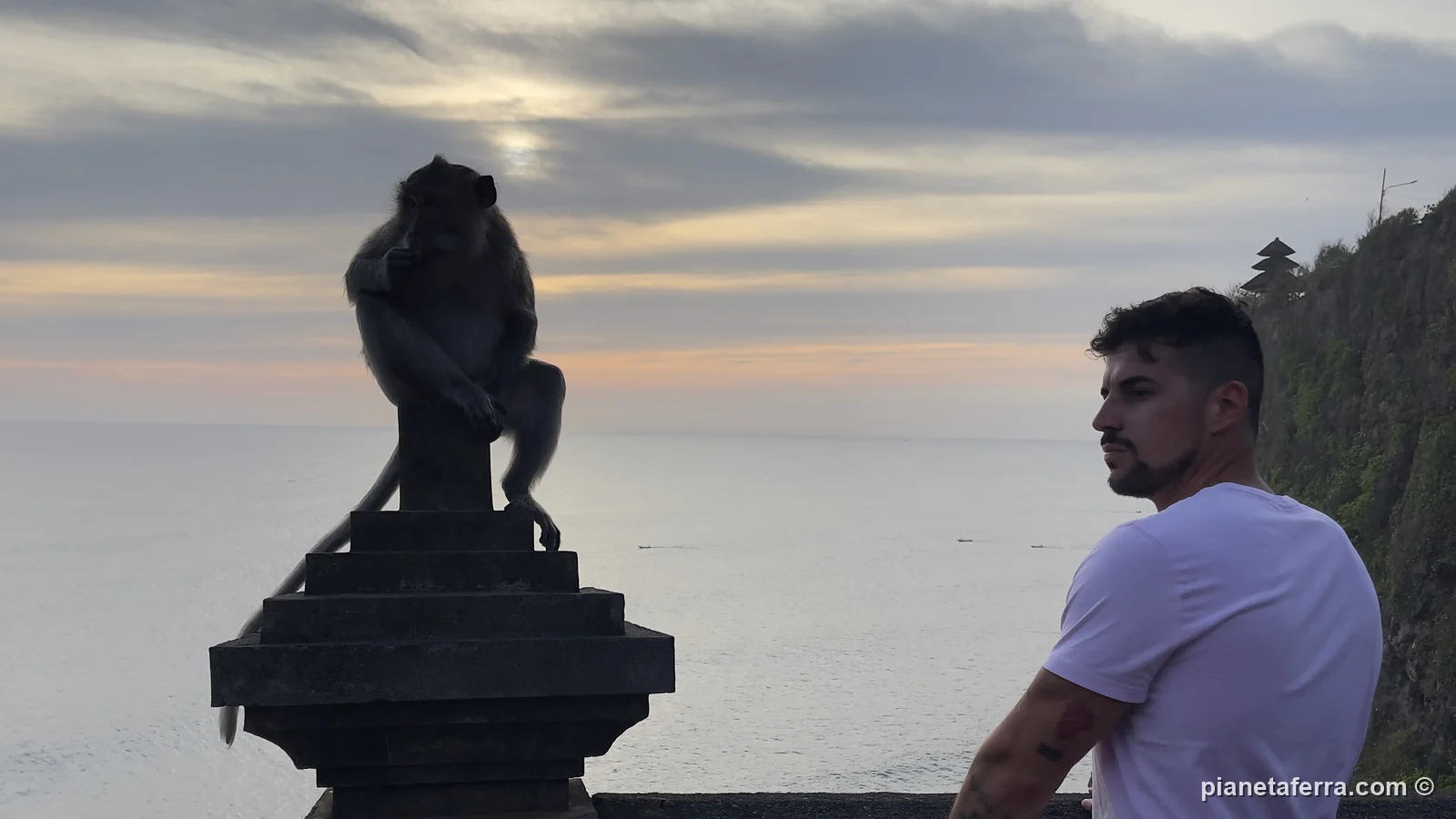 Luca al tramonto al tempio di Uluwatu, con una scimmia sulla colonna