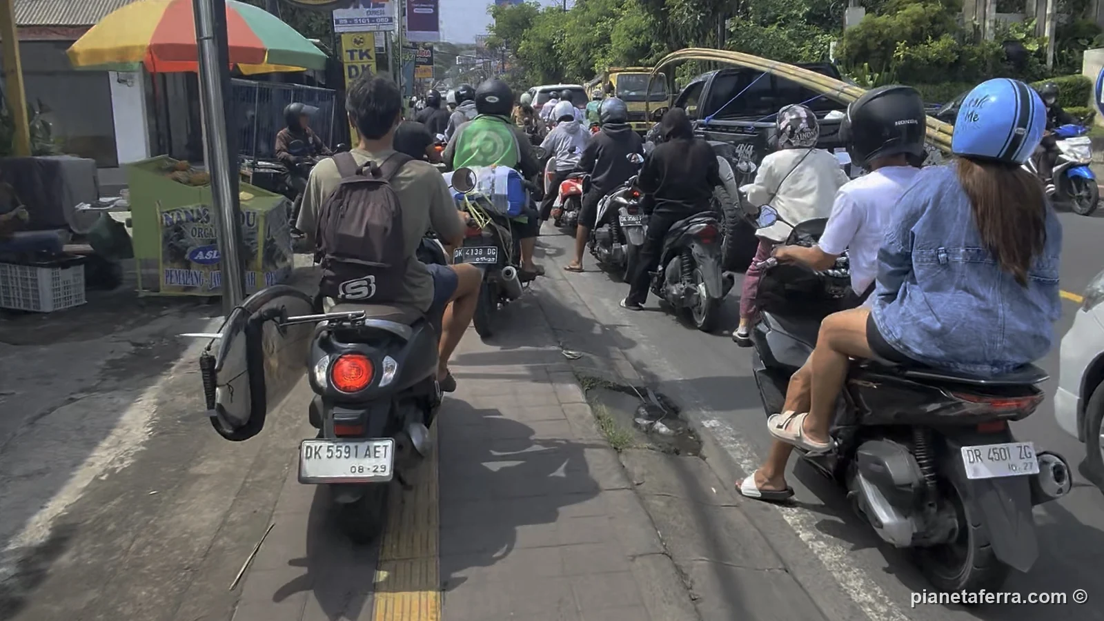 Traffico di scooter su una strada del sud di Bali visto dalla sella di uno scooter, all'inizio del 2026
