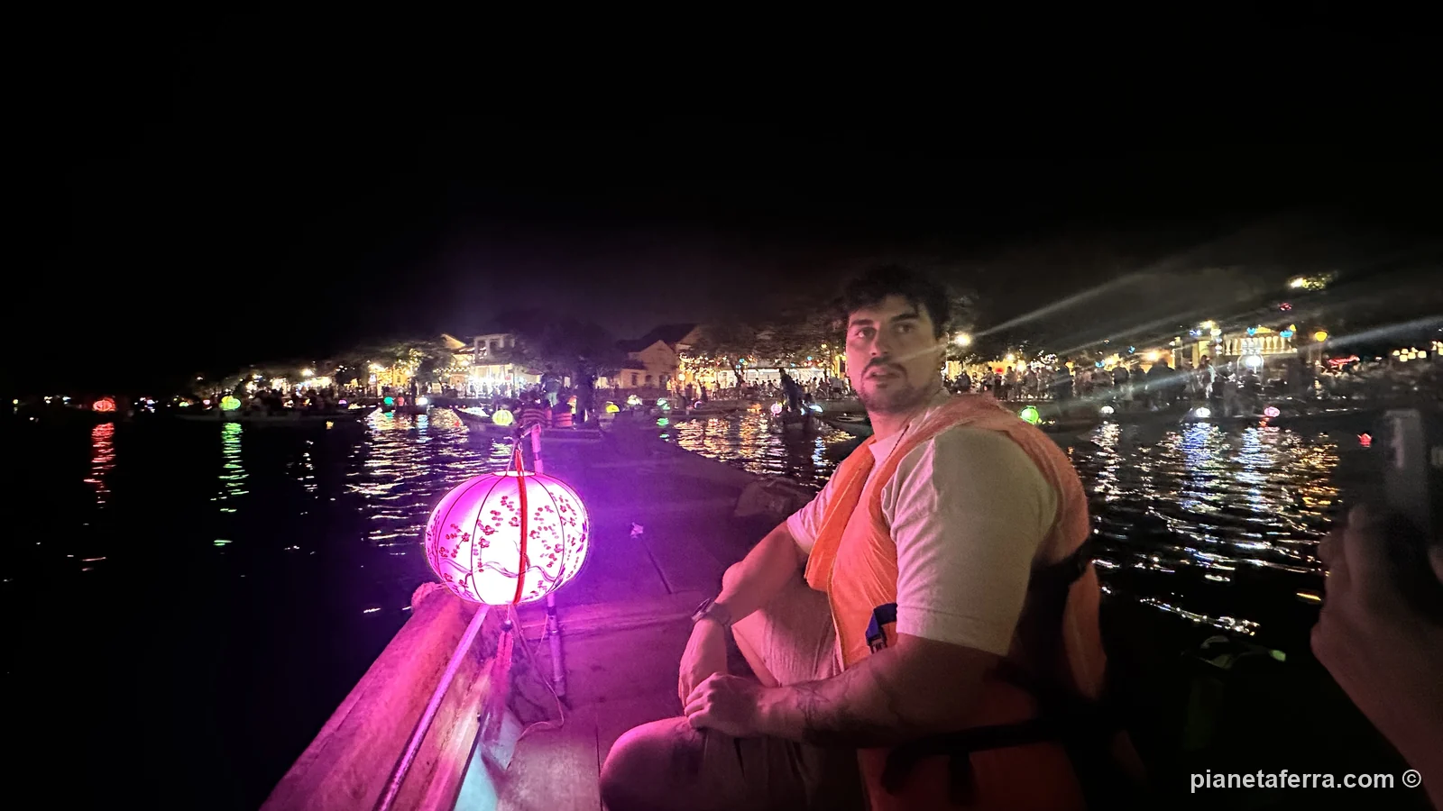 Il fiume Thu Bồn di notte a Hoi An, con una lanterna accesa sulla barca e le luci del centro storico sullo sfondo