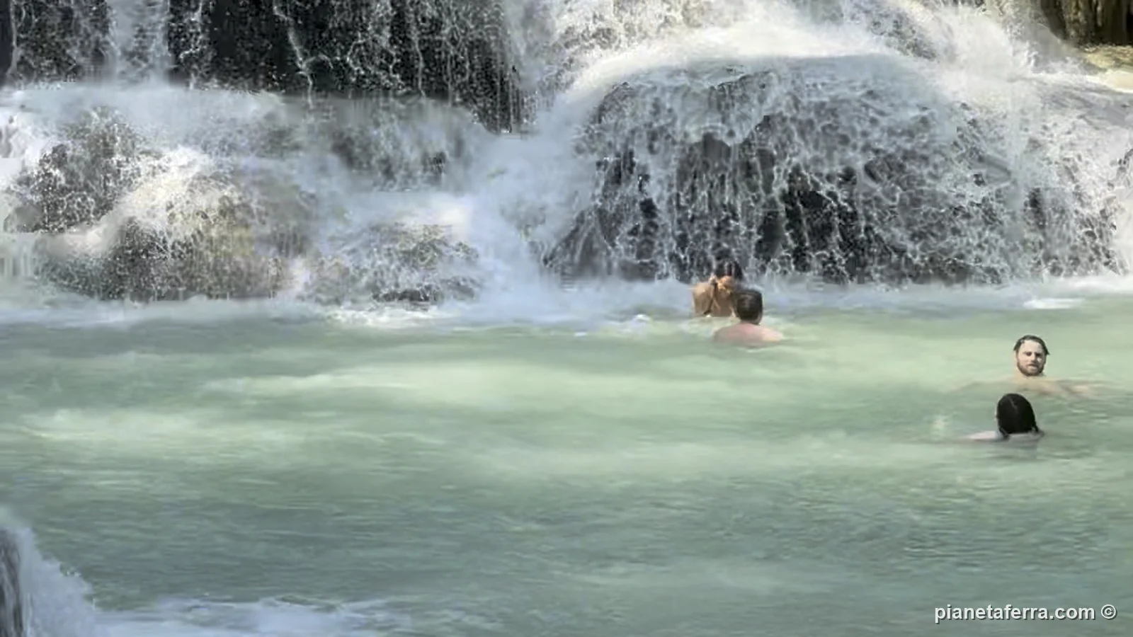 Persone che fanno il bagno nella vasca sotto una delle cascate basse di Kuang Si
