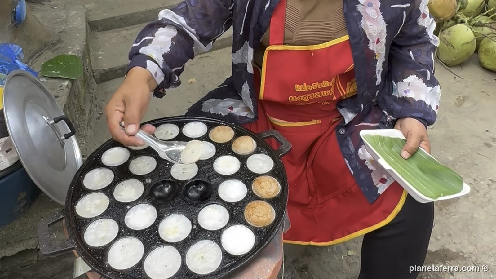 Una signora cuoce i khao nom kok, i dolcetti di riso e cocco, alle bancarelle all'ingresso di Kuang Si