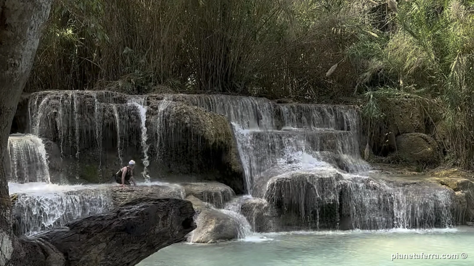 Le cascate basse di Kuang Si con l'acqua turchese e un ragazzo che nuota nella vasca