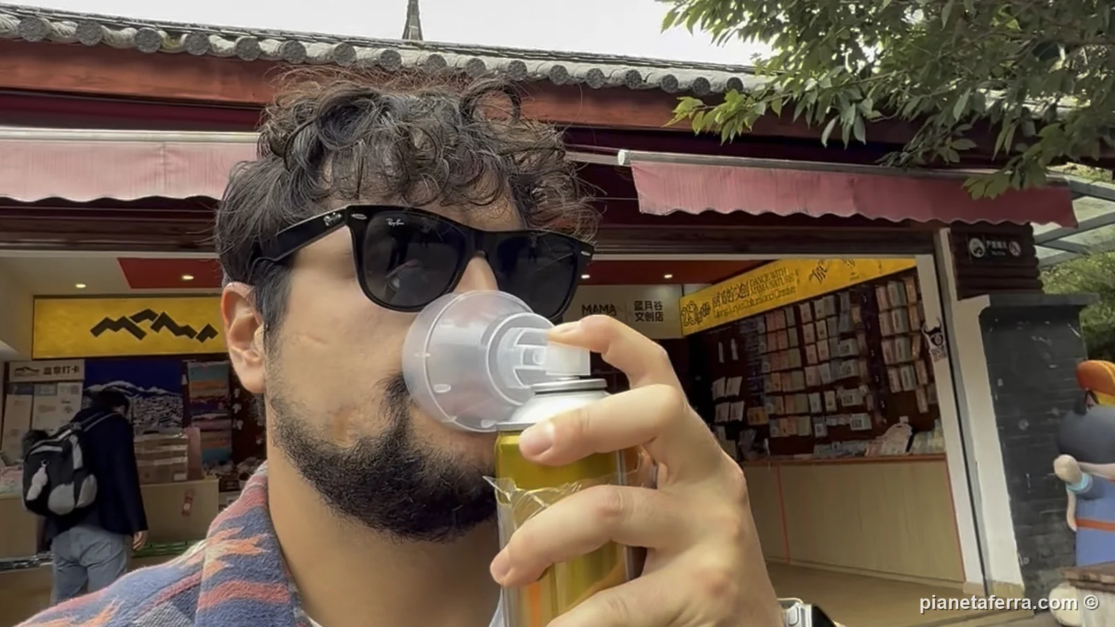 Luca respira da una bomboletta d'ossigeno alla Valle della Luna Blu, nello Yunnan, davanti ai negozi del parco