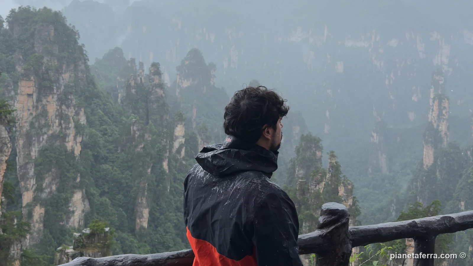 Luca con la giacca antipioggia CMP davanti ai pilastri di roccia di Zhangjiajie, sotto la pioggia, a luglio 2026