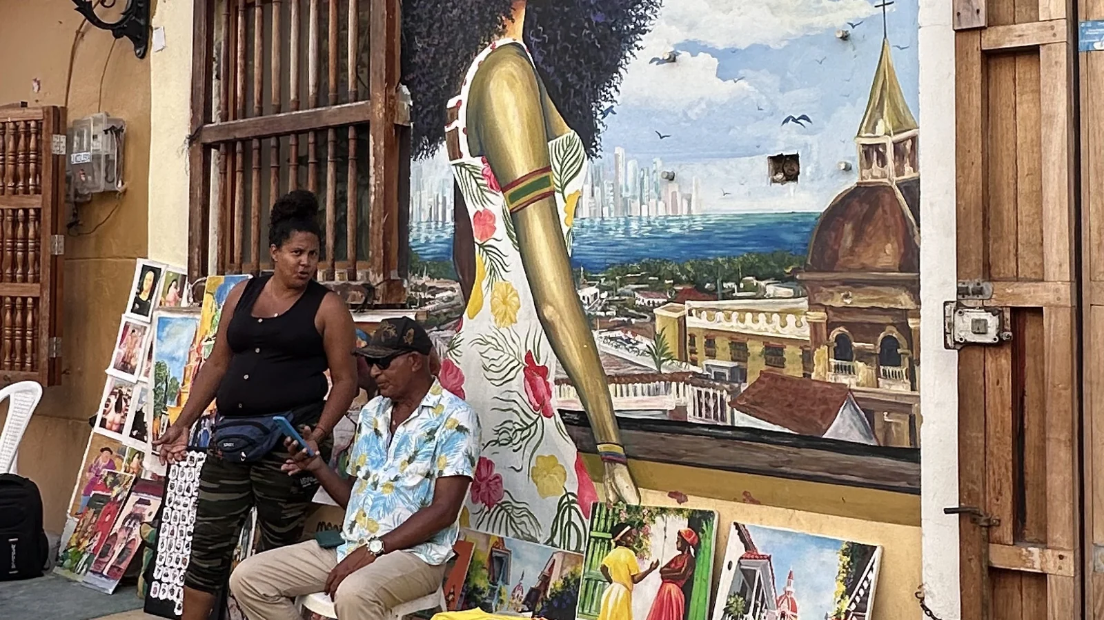 Murales colorati e bandierine nel quartiere di Getsemaní a Cartagena, con venditori di quadri