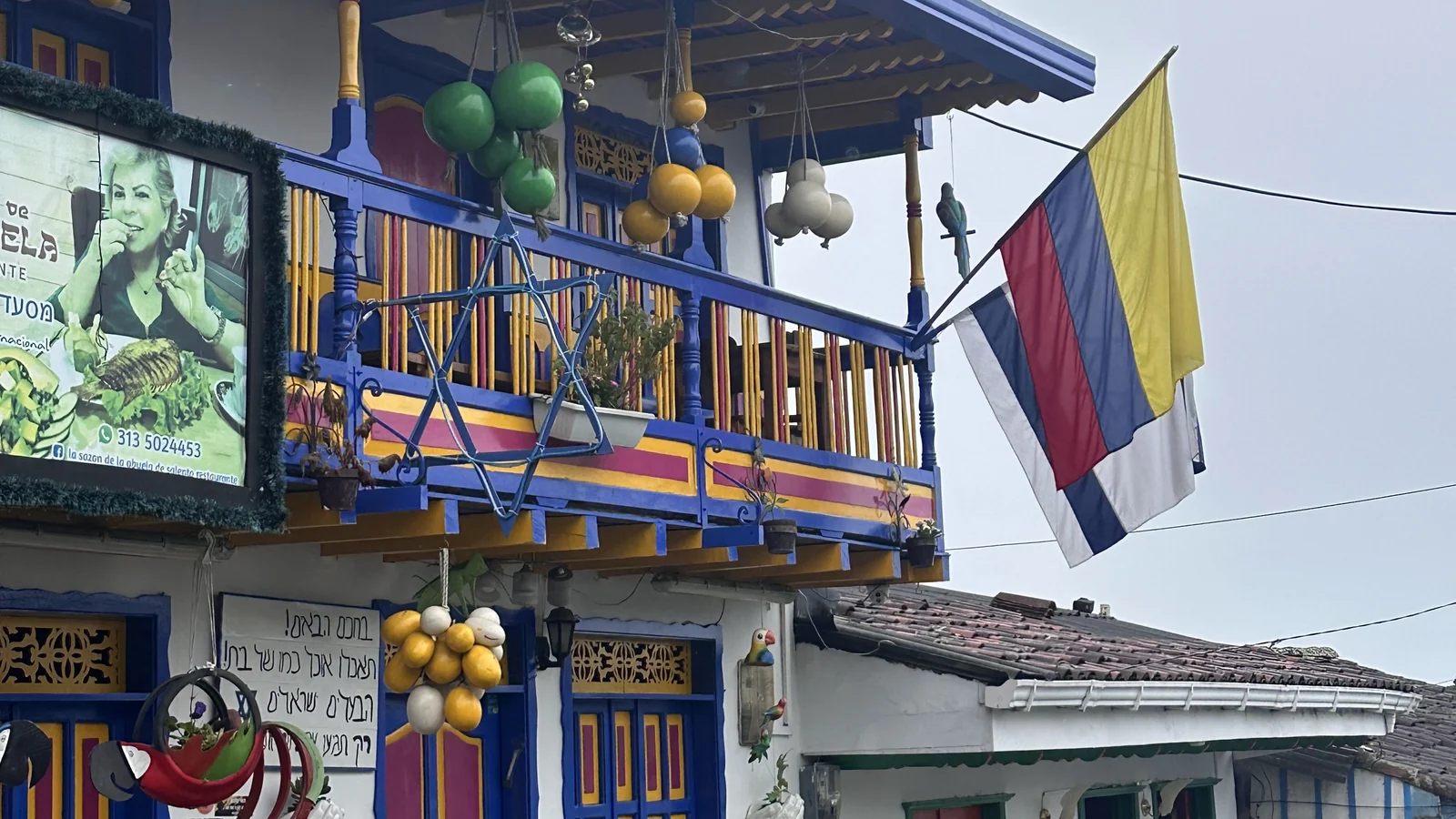 Balcone in legno dipinto di blu con bandiera colombiana su una casa del centro di Salento