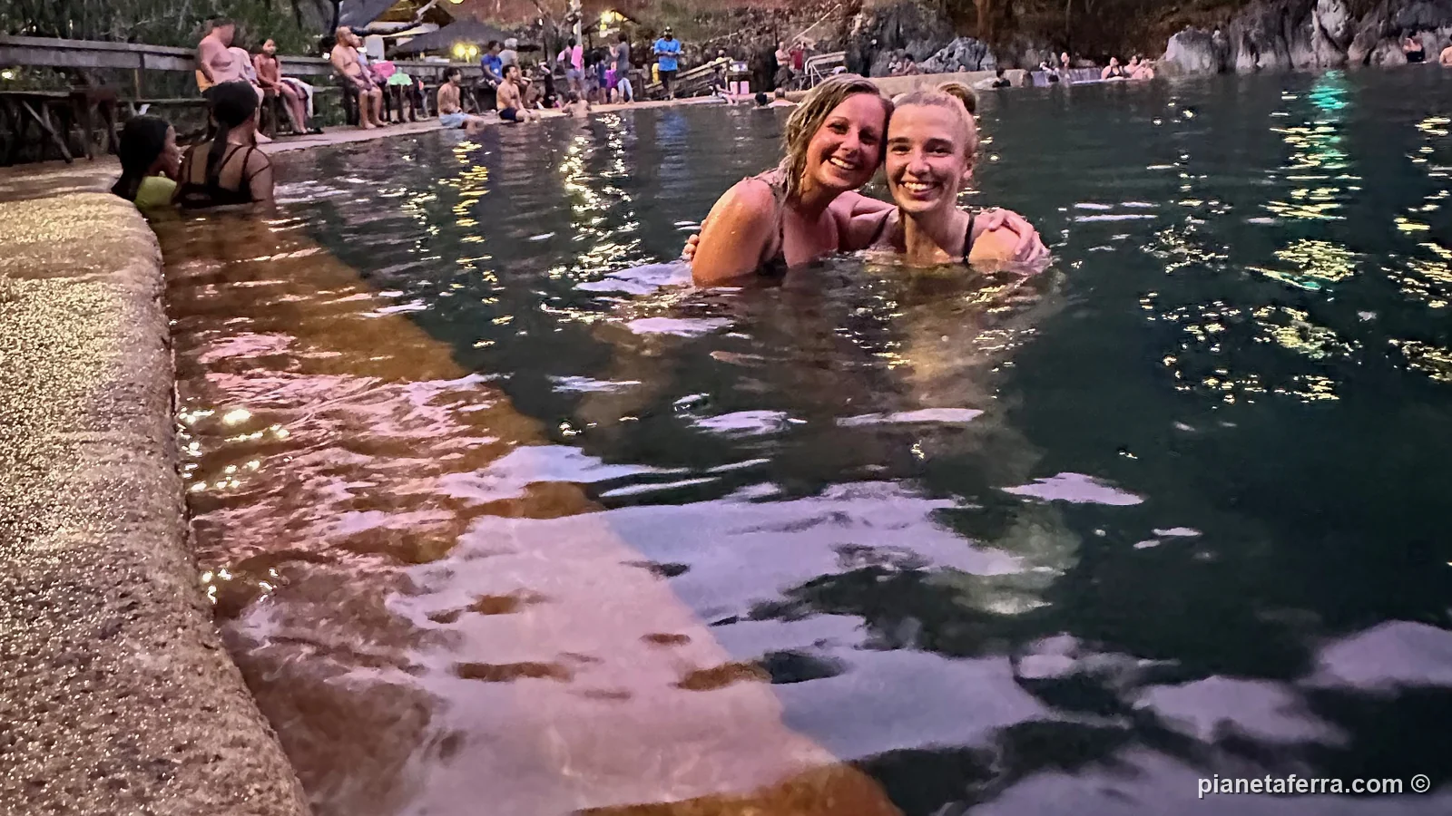 Due amiche nella piscina calda delle terme di Maquinit a Coron, al tramonto, nel 2023