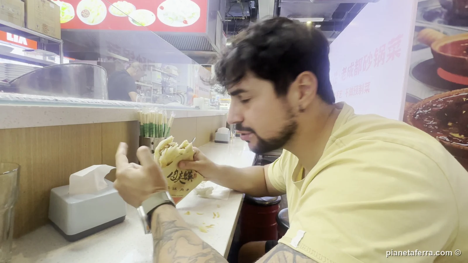 Luca mangia un panino di pasta sfogliata con lo stufato in un locale di Pechino, a maggio 2024