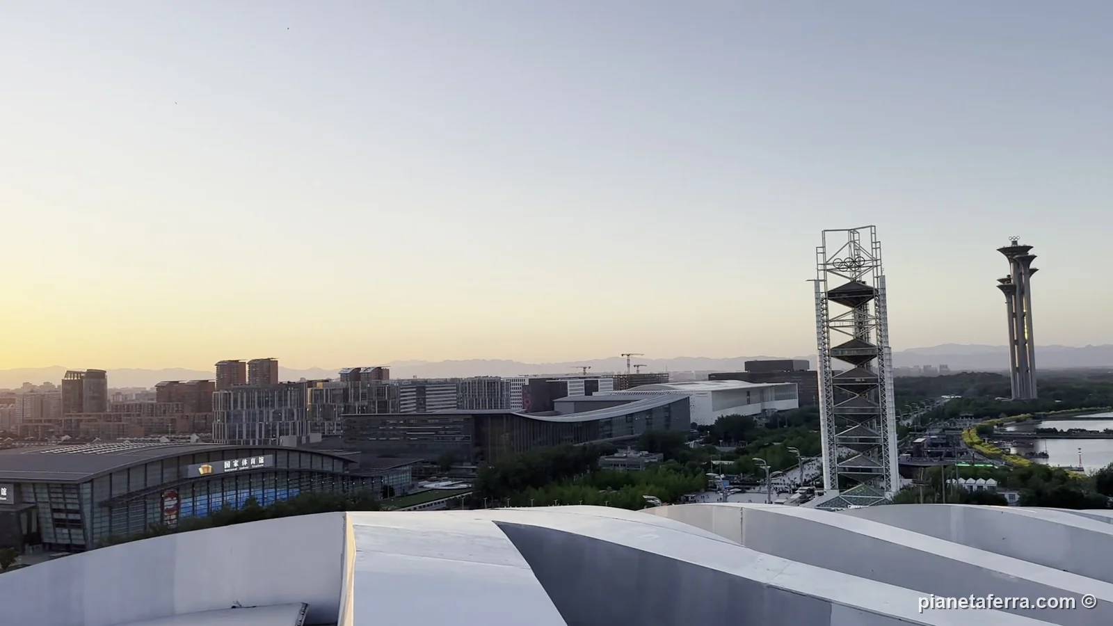 La Torre olimpica e il parco olimpico di Pechino visti dal tetto del Nido d'uccello al tramonto, a maggio 2024