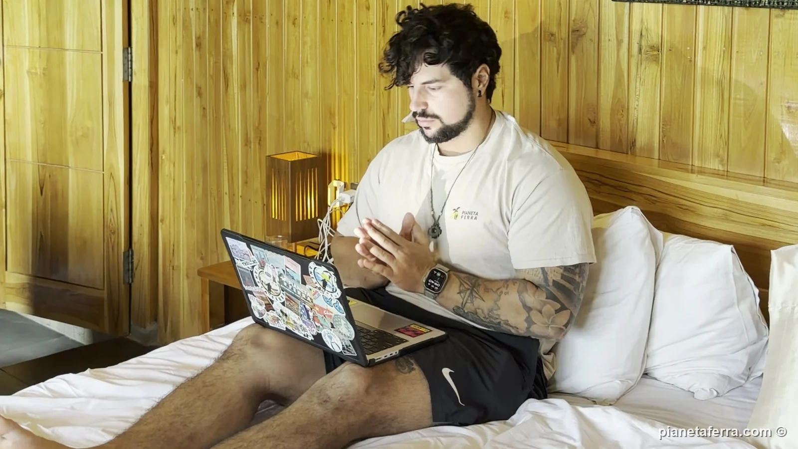 Luca lavora al computer sul letto della camera in legno a Munduk, collegato all'hotspot del telefono