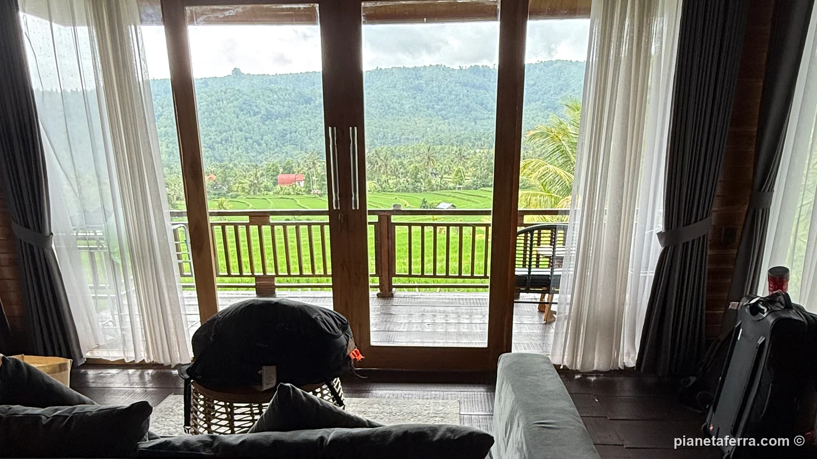 La camera del Mayura Bali Villa con le vetrate aperte sul balcone e sulle risaie, nel nord di Bali