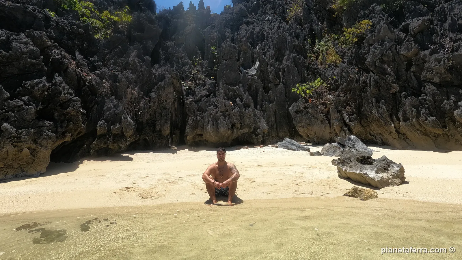 Luca seduto su una spiaggia nascosta tra le rocce calcaree durante un island hopping a El Nido, nel 2024