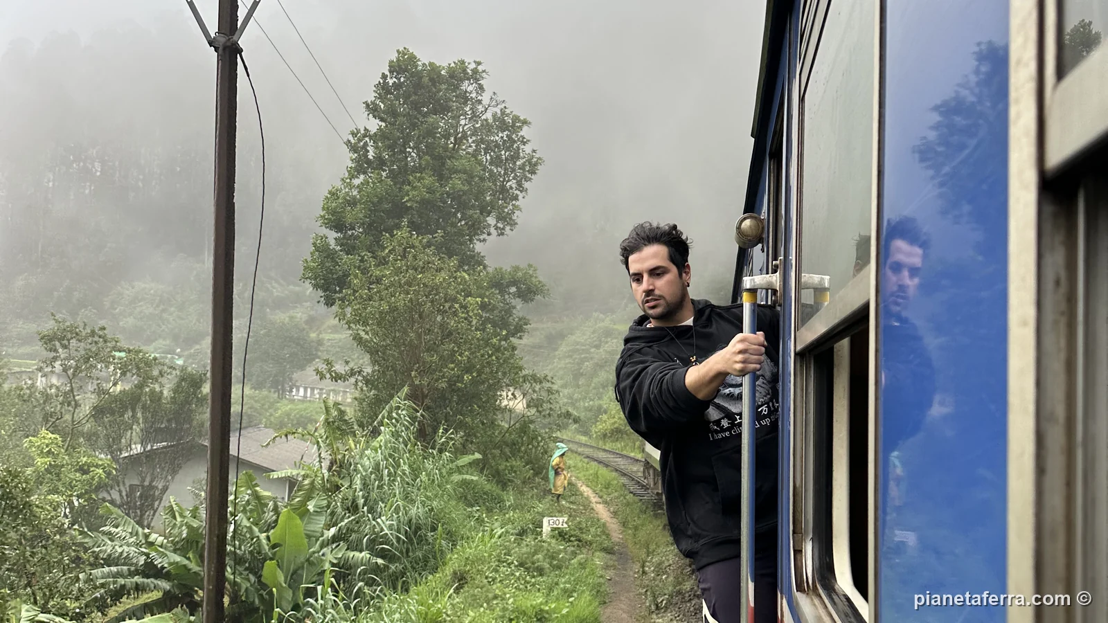Luca Ferraina alla porta aperta del treno tra Nanu Oya ed Ella, nella nebbia delle colline del tè, a maggio 2024
