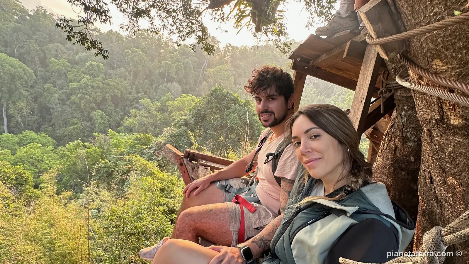 Luca e Patricia seduti sul bordo della casa sull'albero all'alba, sopra la giungla