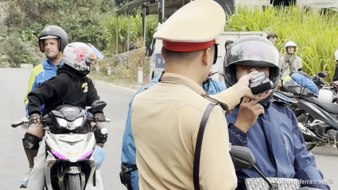 Un agente della polizia stradale vietnamita fa soffiare nell'etilometro un motociclista sull'Ha Giang Loop, a ottobre 2026