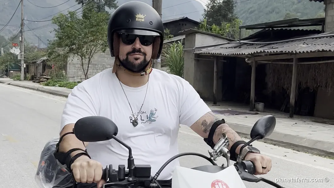 Luca in sella a una Honda XR rossa su una strada dell'Ha Giang Loop, con le montagne dietro, a ottobre 2026