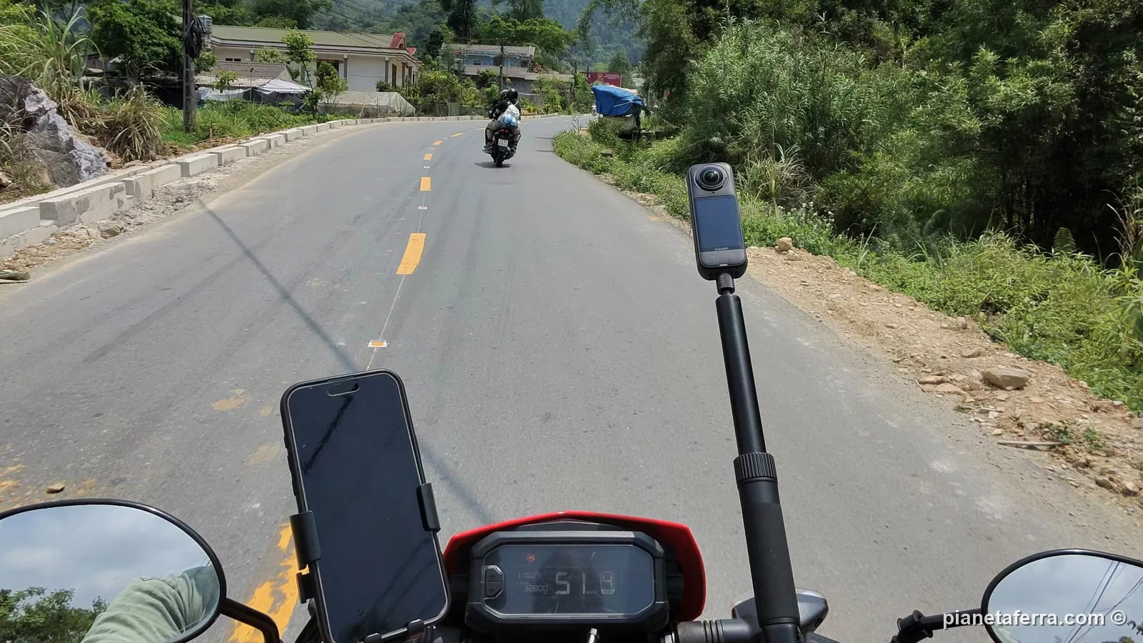 La strada dell'Ha Giang Loop vista dalla sella della moto, con un'altra moto davanti, nella primavera del 2026