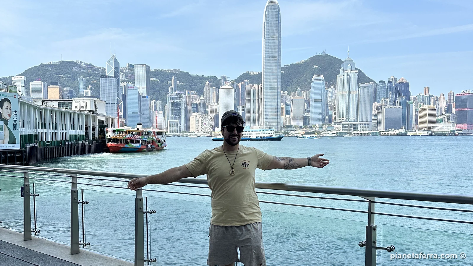Luca sul lungomare di Tsim Sha Tsui con lo skyline dell'isola di Hong Kong e lo Star Ferry, a maggio 2024