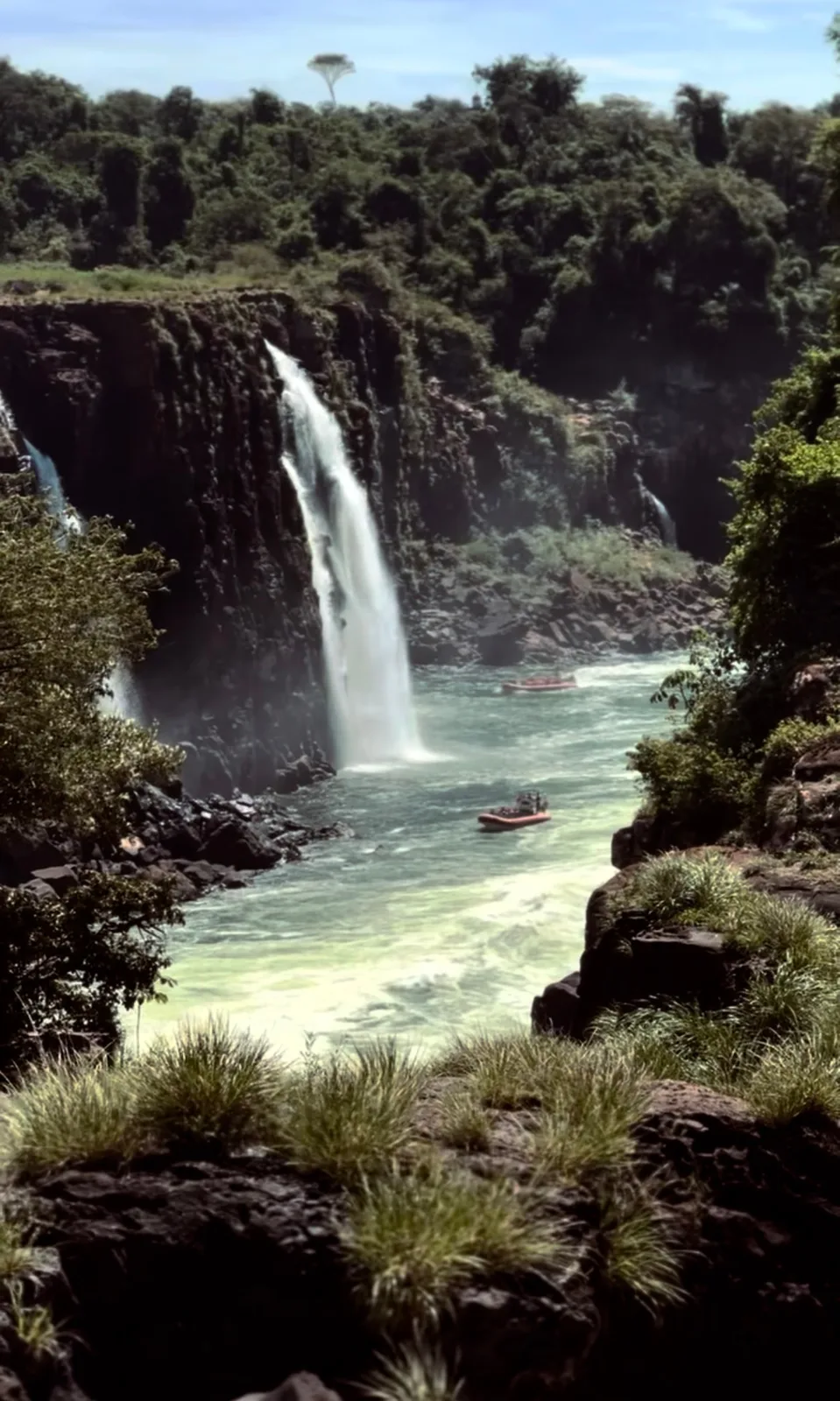 Gommoni sul fiume sotto una cascata di Iguazú durante l'escursione in barca