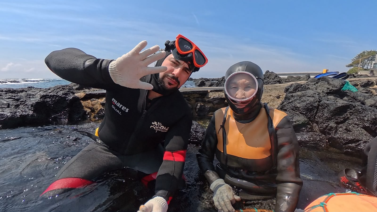 Luca Ferra in muta insieme a una haenyeo di Jeju sulle rocce laviche dopo l'immersione