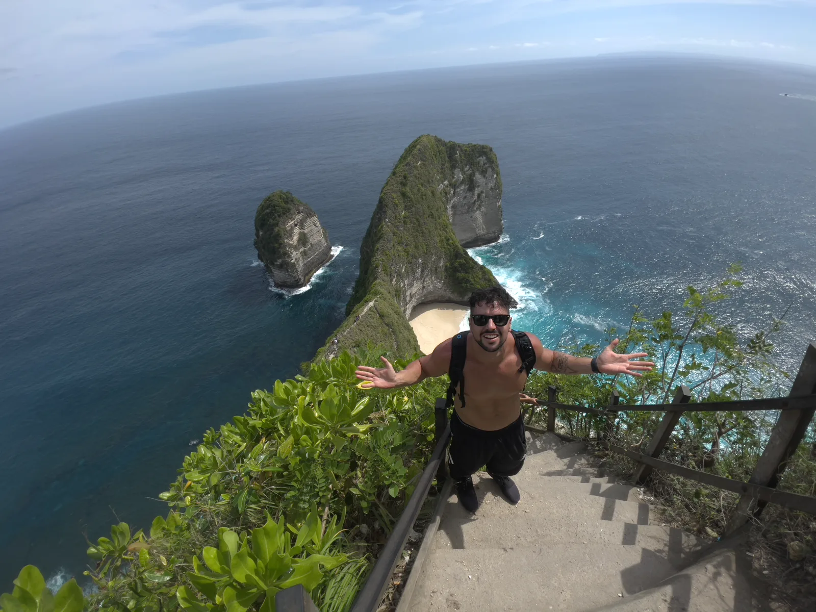 Luca a braccia aperte sul sentiero di Kelingking Beach a Nusa Penida, Bali, durante il suo primo viaggio da solo