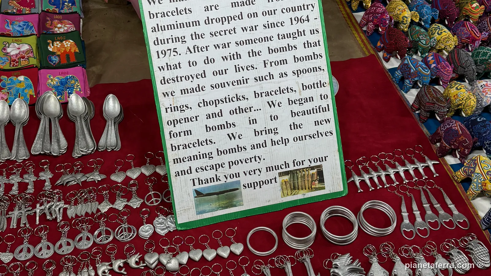 Braccialetti e cucchiai fatti con l'alluminio delle bombe in vendita al mercato notturno di Luang Prabang, con il cartello che racconta la loro storia