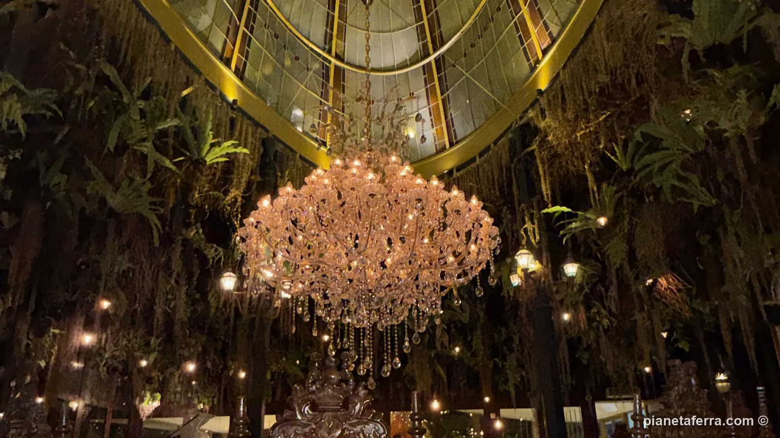 La sala di Merlin's a Ubud, con la cupola di vetro, il lampadario di cristallo e le piante