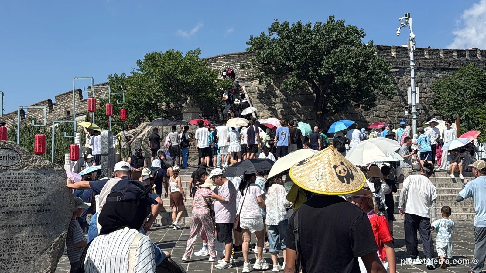 Folla con ombrelli e cappelli sulla Grande Muraglia di Mutianyu a luglio, nel primo pomeriggio