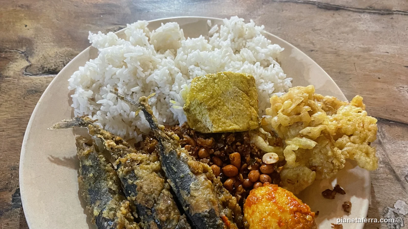 Nasi campur con pesce fritto, riso, arachidi e verdure in un warung di Nusa Penida
