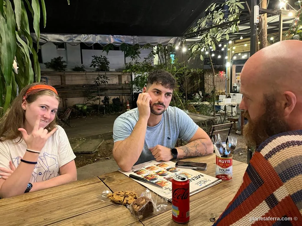 Tre viaggiatori seduti al tavolo dell'area comune di un ostello di Bangkok, in Thailandia