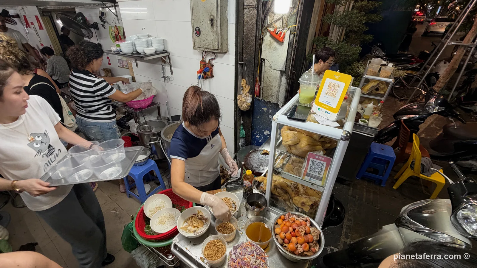 Il banco di Phở Hà sul marciapiede di Hàng Hòm, con i polli lessi nella vetrinetta, la ciotola di trứng non e le ciotole pronte per il phở