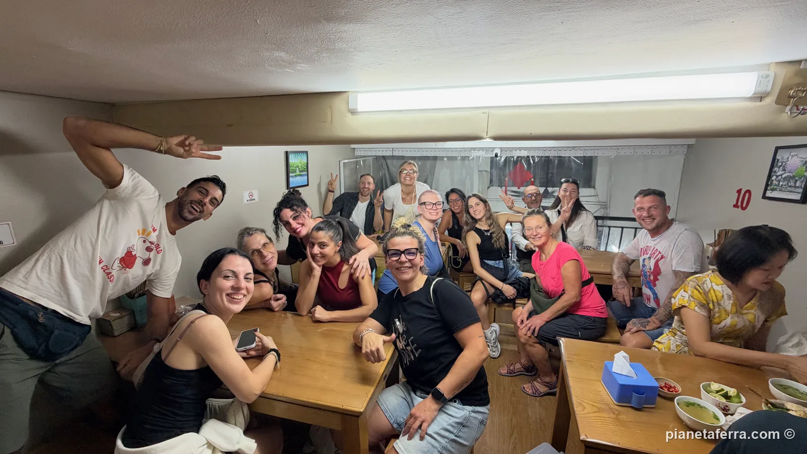 Il gruppo di Pianeta Ferra a cena al piano di sopra di Phở Hà, con il soffitto bassissimo e le ciotole di phở sui tavoli