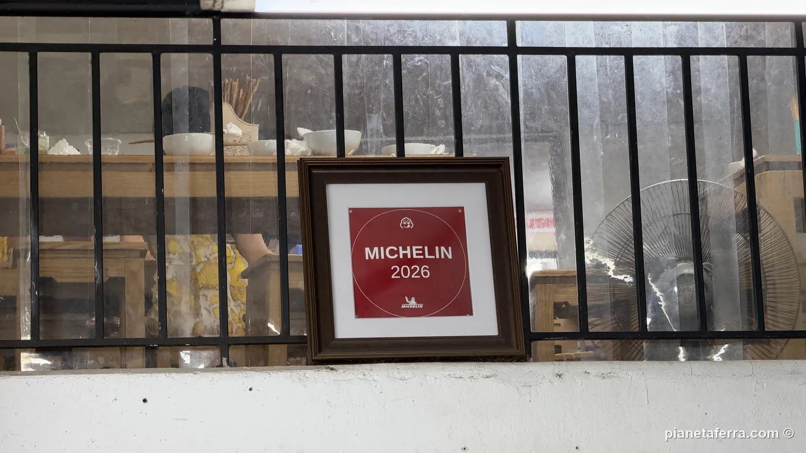 La targa rossa Michelin 2026 con l'omino Bibendum, esposta dentro Phở Hà ad Hanoi