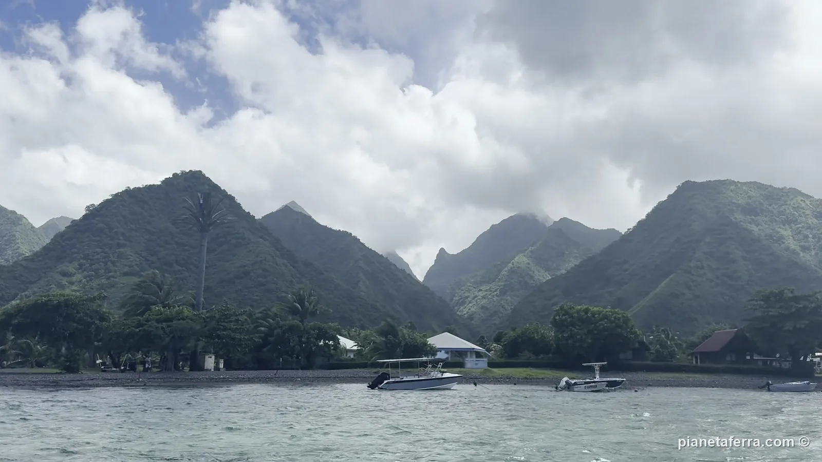 Le montagne verdi di Tahiti Iti con il sole tra le nuvole, viste dalla barca nella laguna