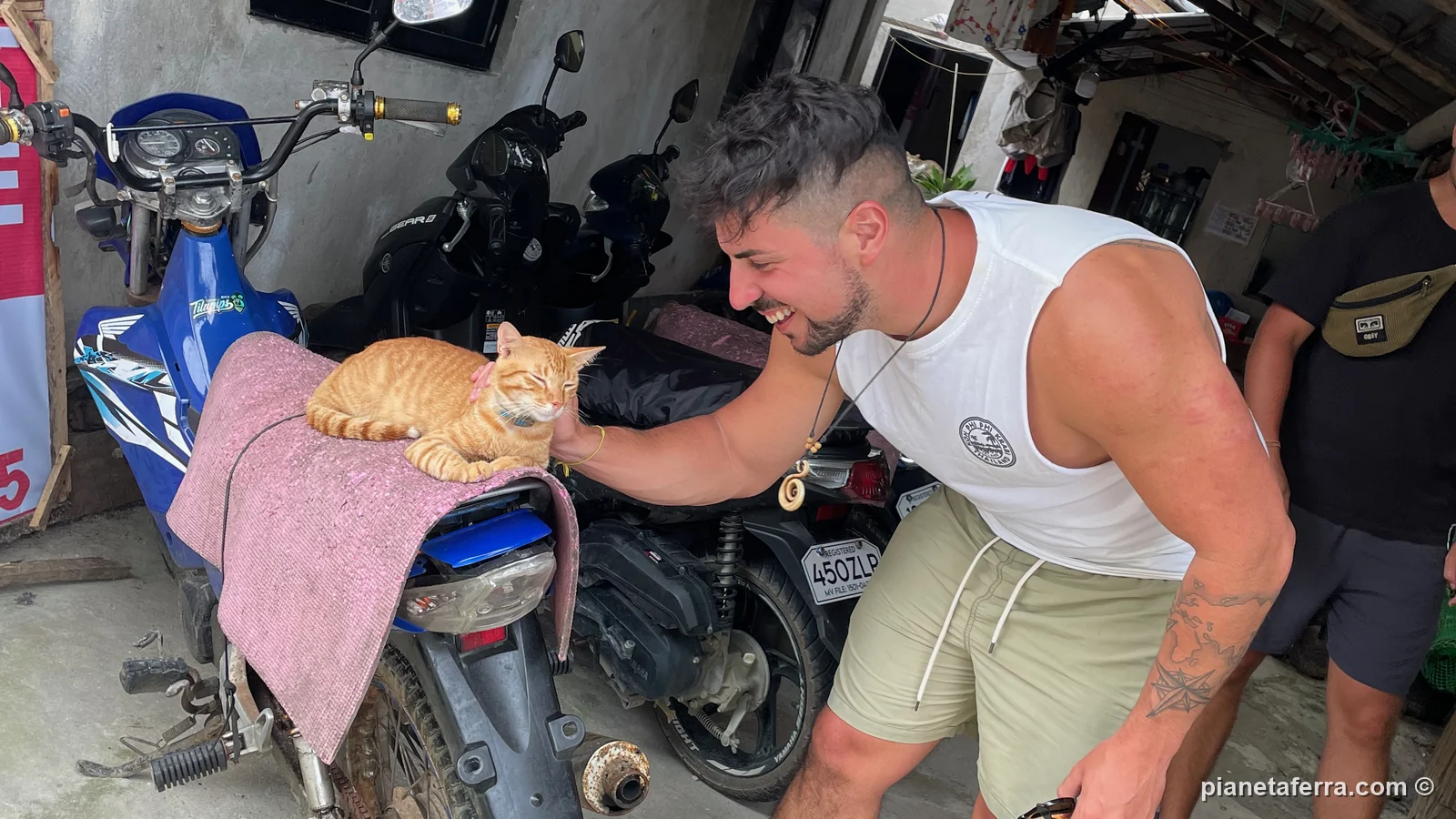 Luca accarezza un gatto sulla sella di uno scooter a Siargao, nel 2023