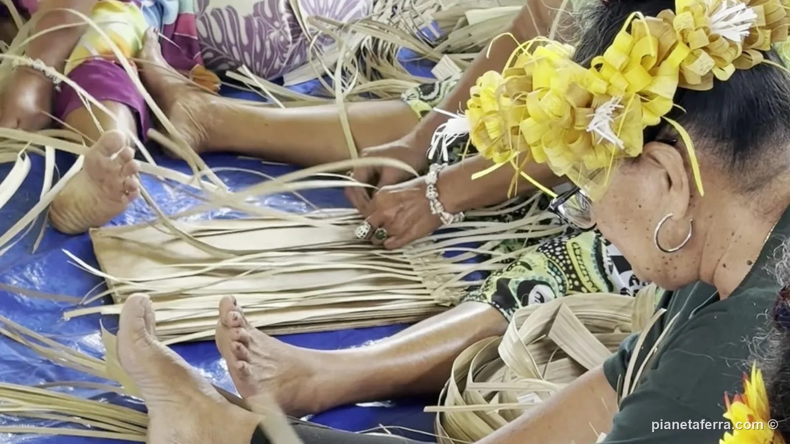 Le artigiane di Rurutu con le corone di fiori intrecciano le foglie di pandano al villaggio artigianale