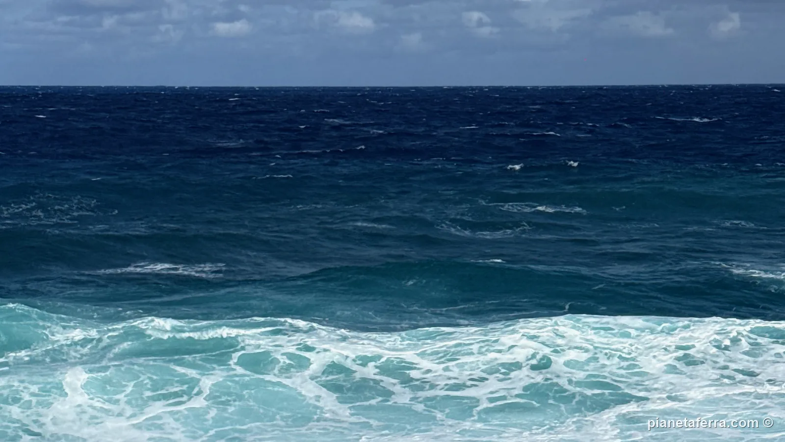 Il mare mosso e le onde bianche sotto le scogliere di Rurutu, il giorno del vento forte