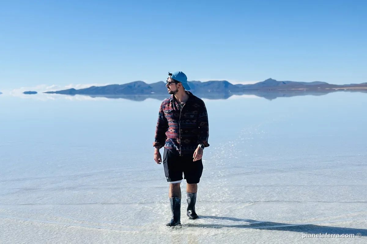 In piedi sul velo d'acqua del Salar de Uyuni con stivali di gomma