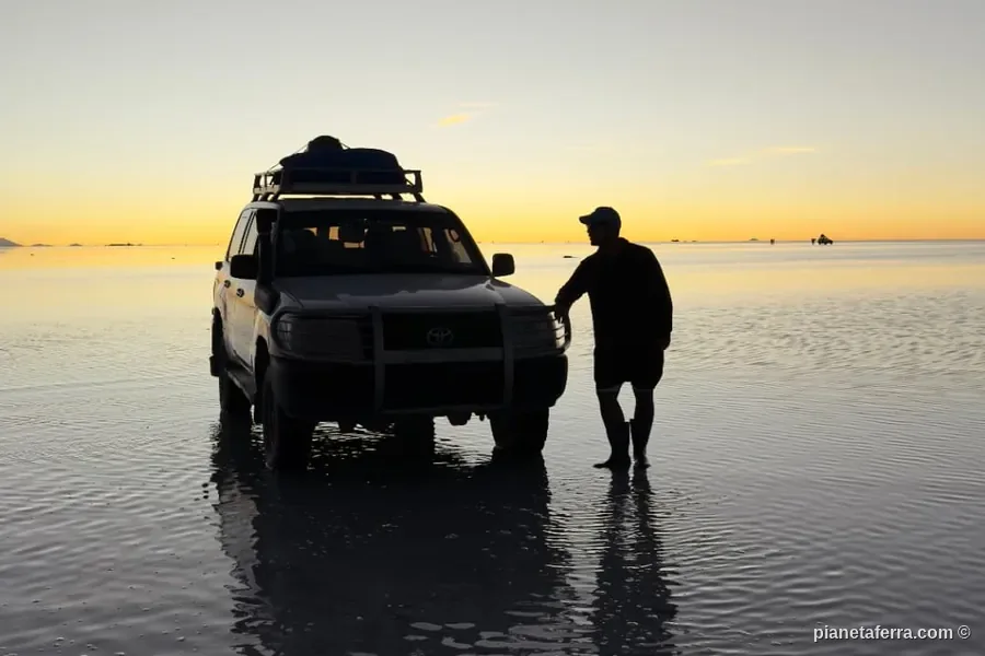 Il 4x4 del tour fermo sull'acqua del Salar de Uyuni al tramonto
