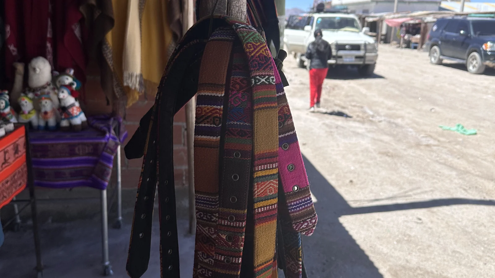 Tessuti andini e cinture colorate appesi davanti a un negozio di artigianato su una strada sterrata di San Pedro de Atacama