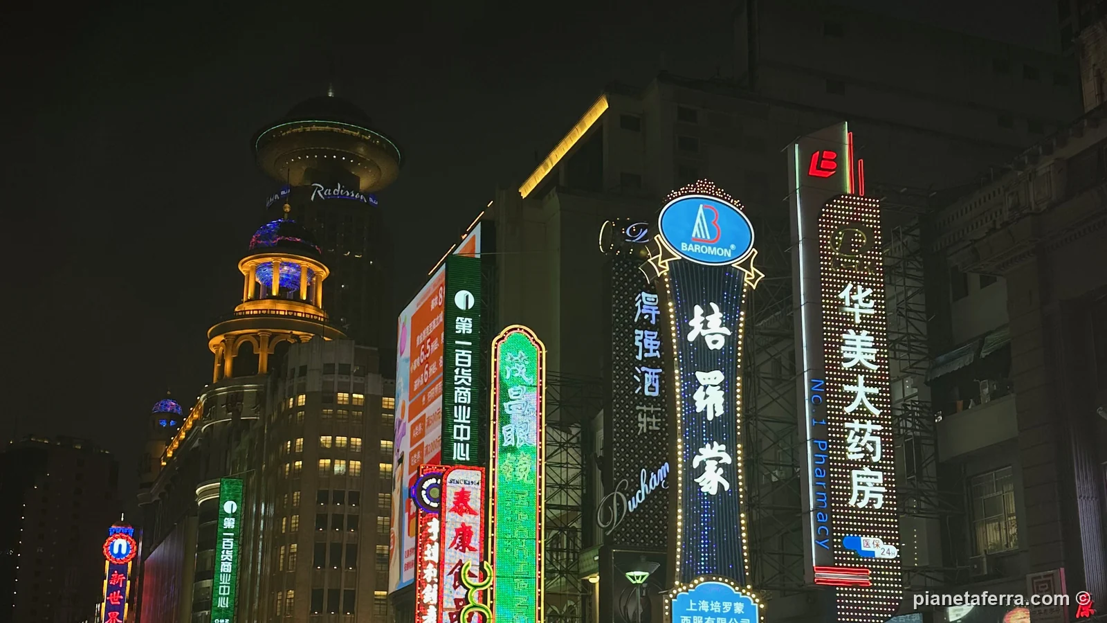 Le insegne al neon di Nanjing Road a Shanghai di sera, sotto la pioggia, nel 2024