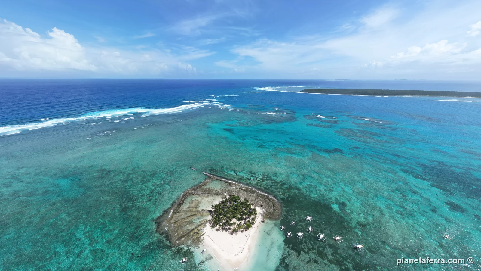 Guyam Island con il palmeto al centro e la barriera corallina intorno, vista dal drone, nel 2023