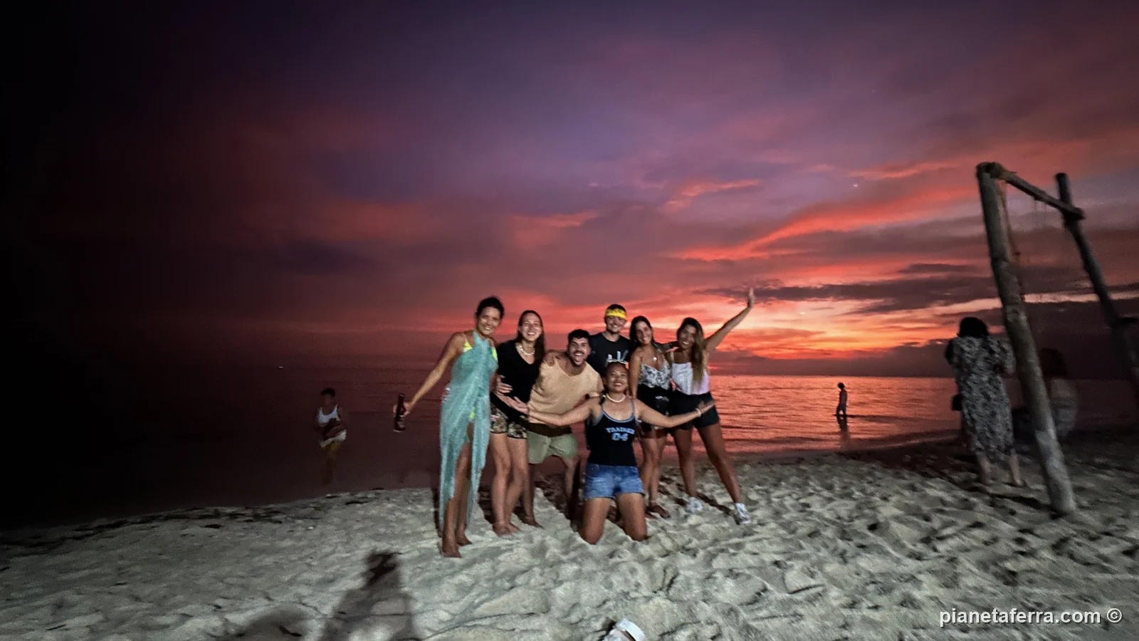 Il gruppo dell'ostello sulla spiaggia di Paliton al tramonto, accanto all'altalena di legno, nel 2023