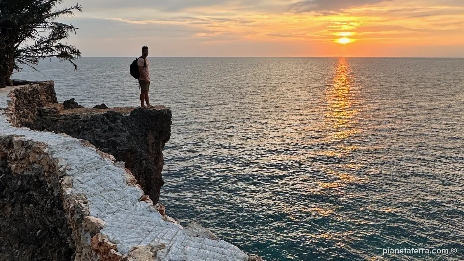 Un ragazzo in piedi sulla scogliera sul mare al tramonto a Siquijor, nel 2023