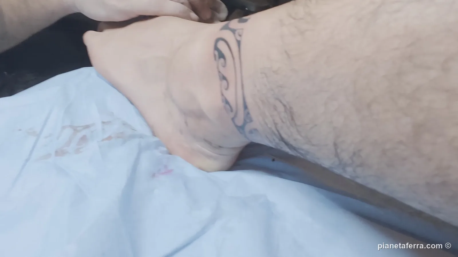 Le linee della cavigliera polinesiana appena tatuate, con la mano di Makalio che tende la pelle