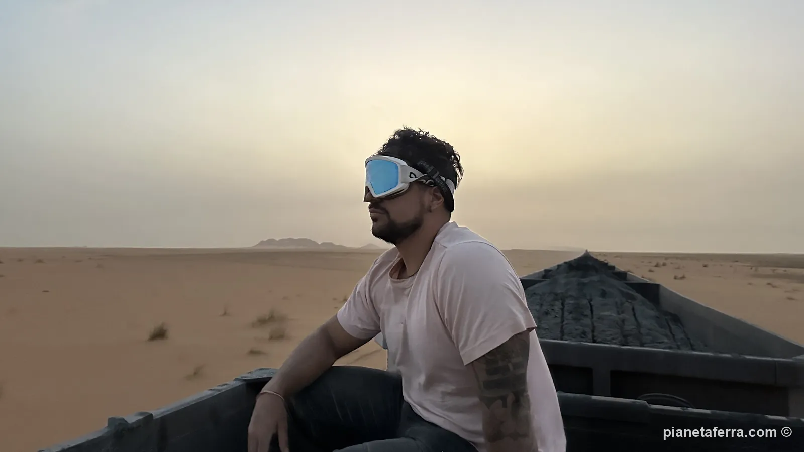 Luca seduto sul minerale di ferro all'alba, con il treno che attraversa il deserto della Mauritania
