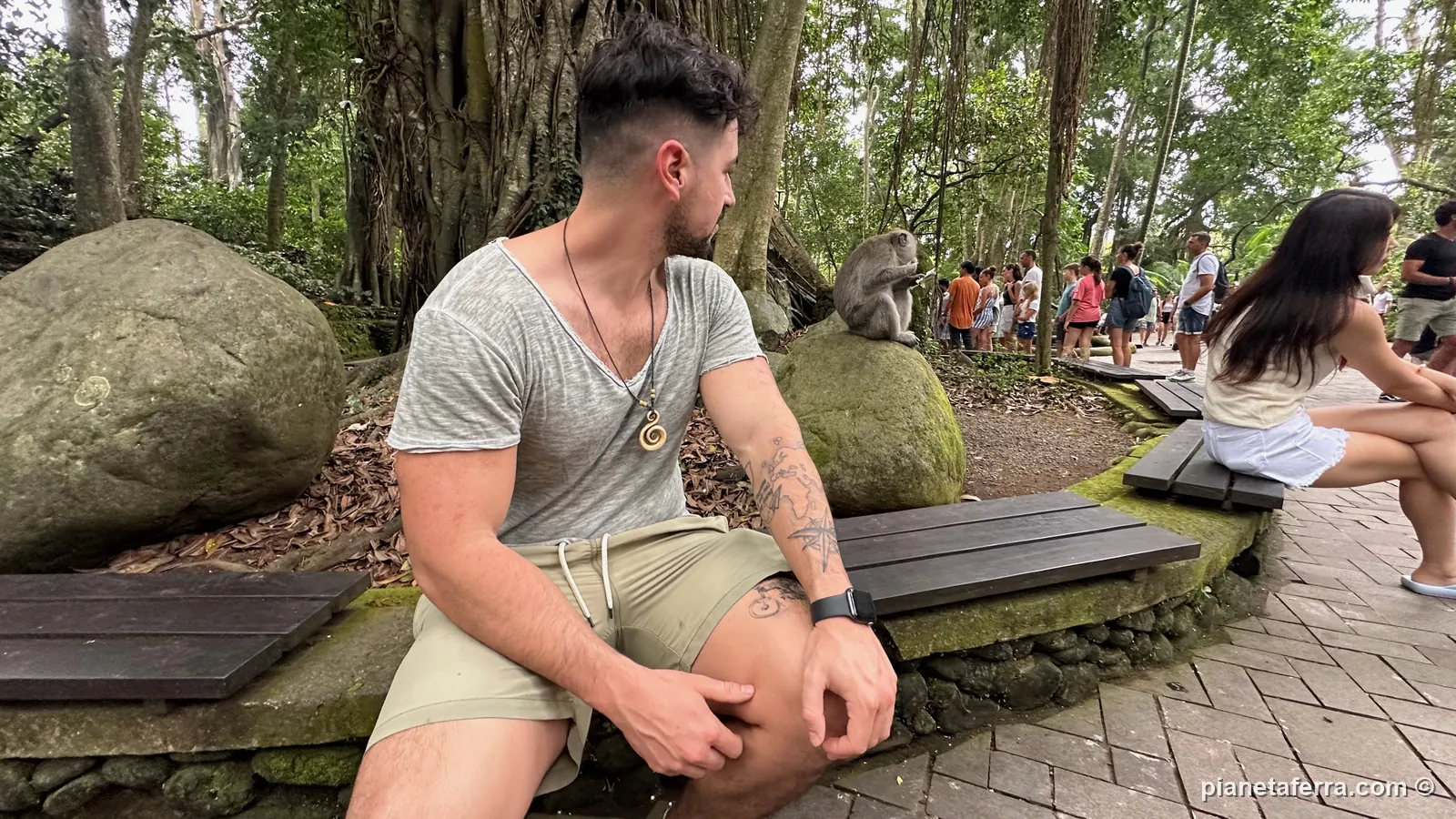 Luca seduto nella Monkey Forest di Ubud con una scimmia sulla roccia alle spalle