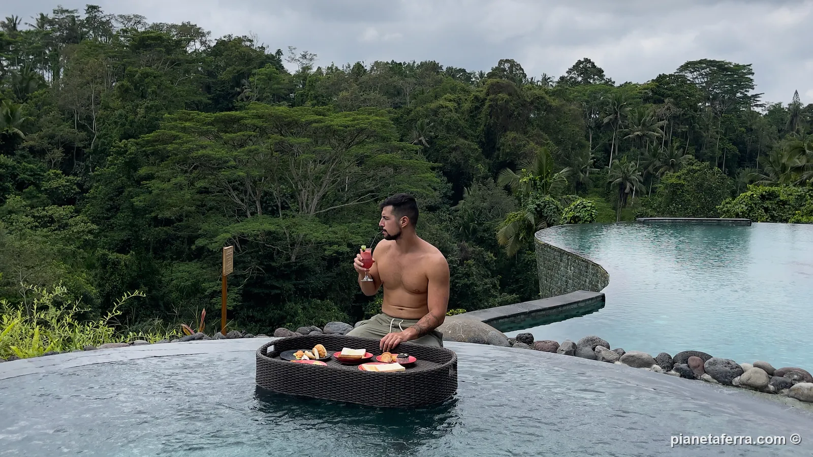 Luca nella piscina a sfioro sulla giungla intorno a Ubud con la colazione galleggiante